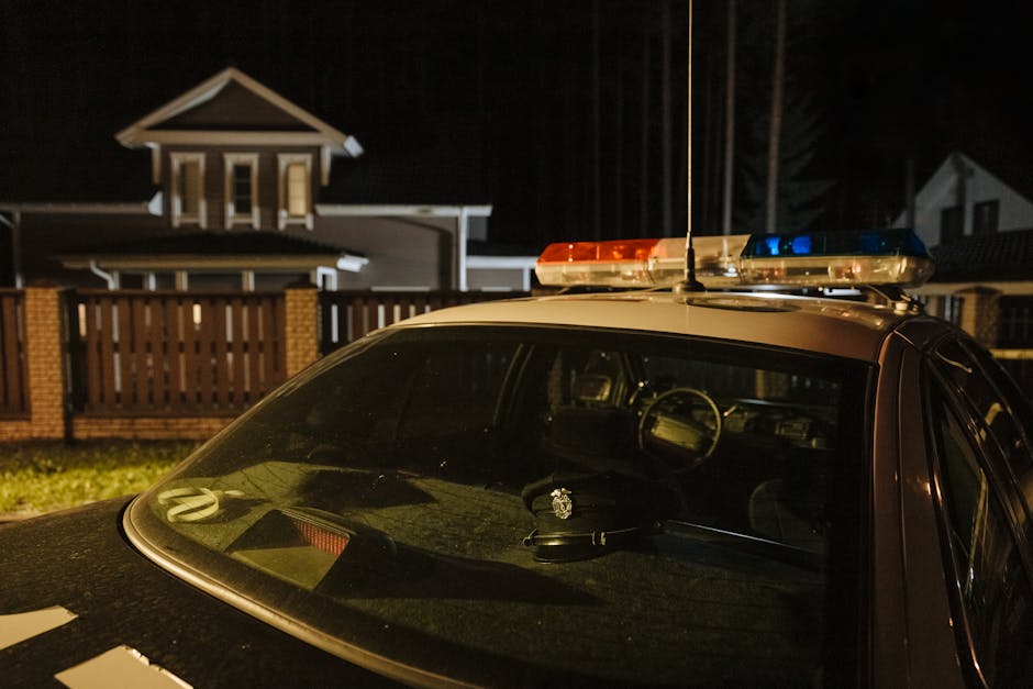 A police car parked at night in front of suburban houses, creating a dramatic scene